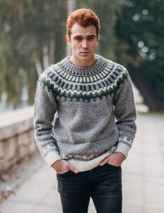 One young handsome man dressed in modern winter sweater walking outdoors in the city.